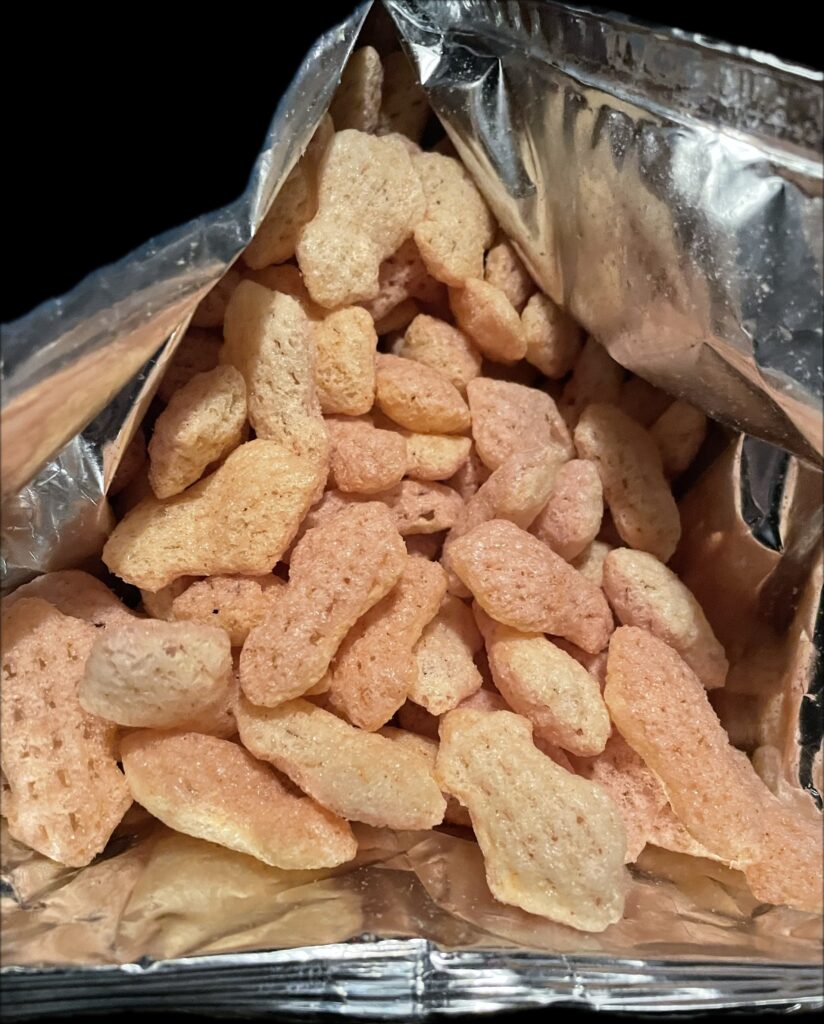 opened bag showing the snack’s golden color and light texture. it gives a mild impression compared to typical spicy korean snack flavors.