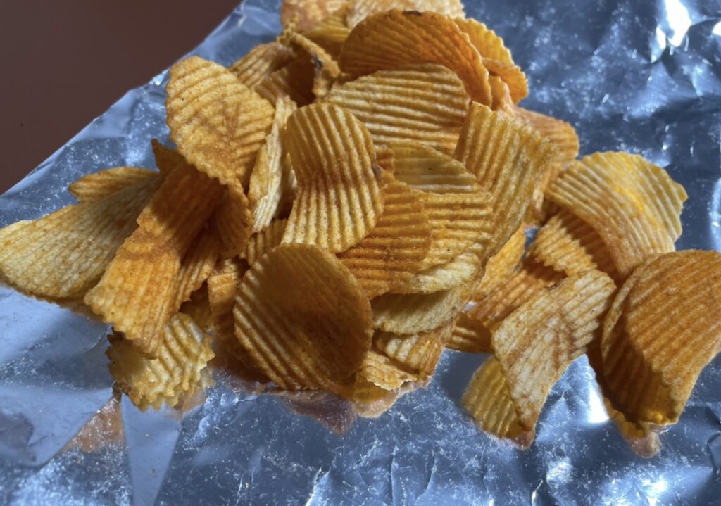 potato chips k-yangnyeom chicken spread out after opening the bag, giving a visual sense of the korean snack flavors through the shape and coating of the chips.
