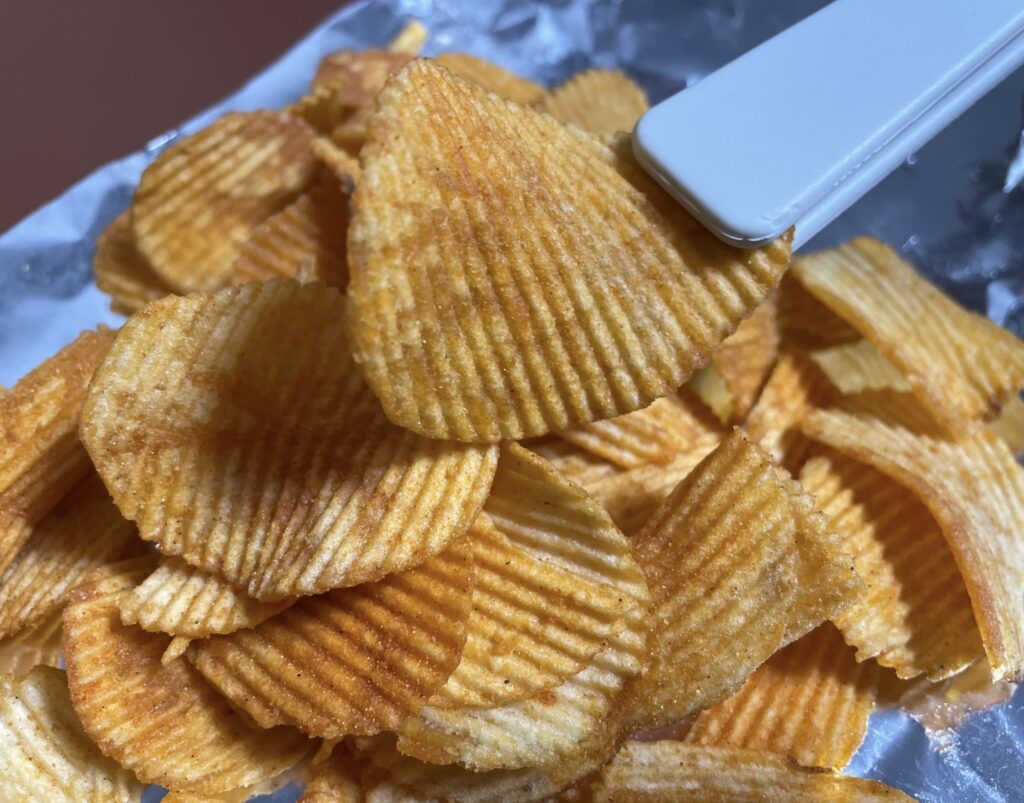 a close-up of a potato chips k-yangnyeom chicken piece, showing its texture and seasoning clearly, suitable for a detailed korean snack review