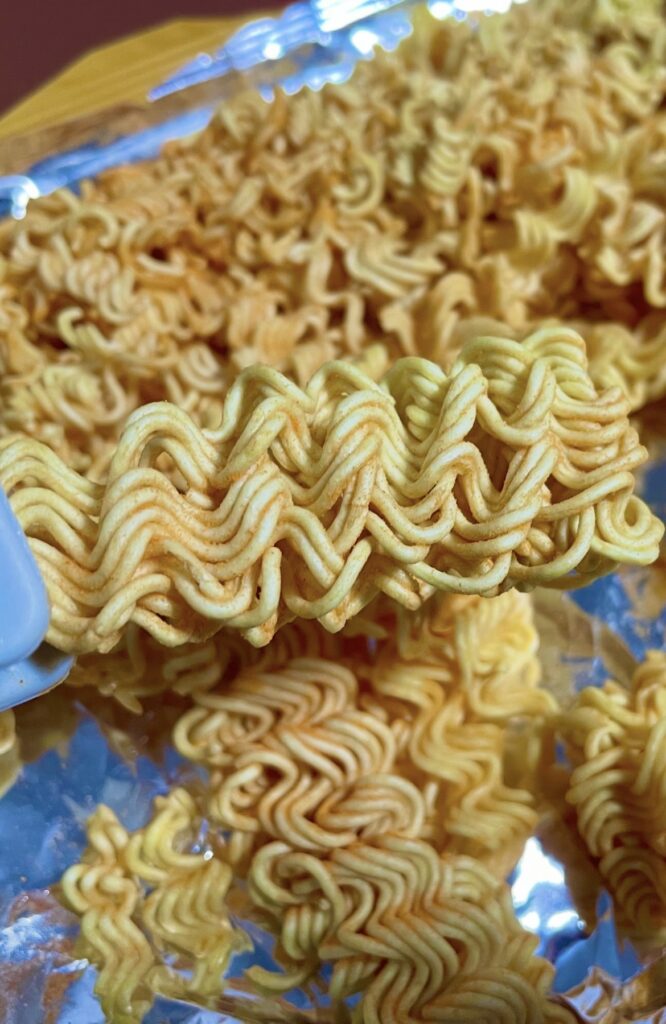 A close-up of the crushed noodle pieces showing their crisp texture and even seasoning — perfect for a detailed korean snack review image