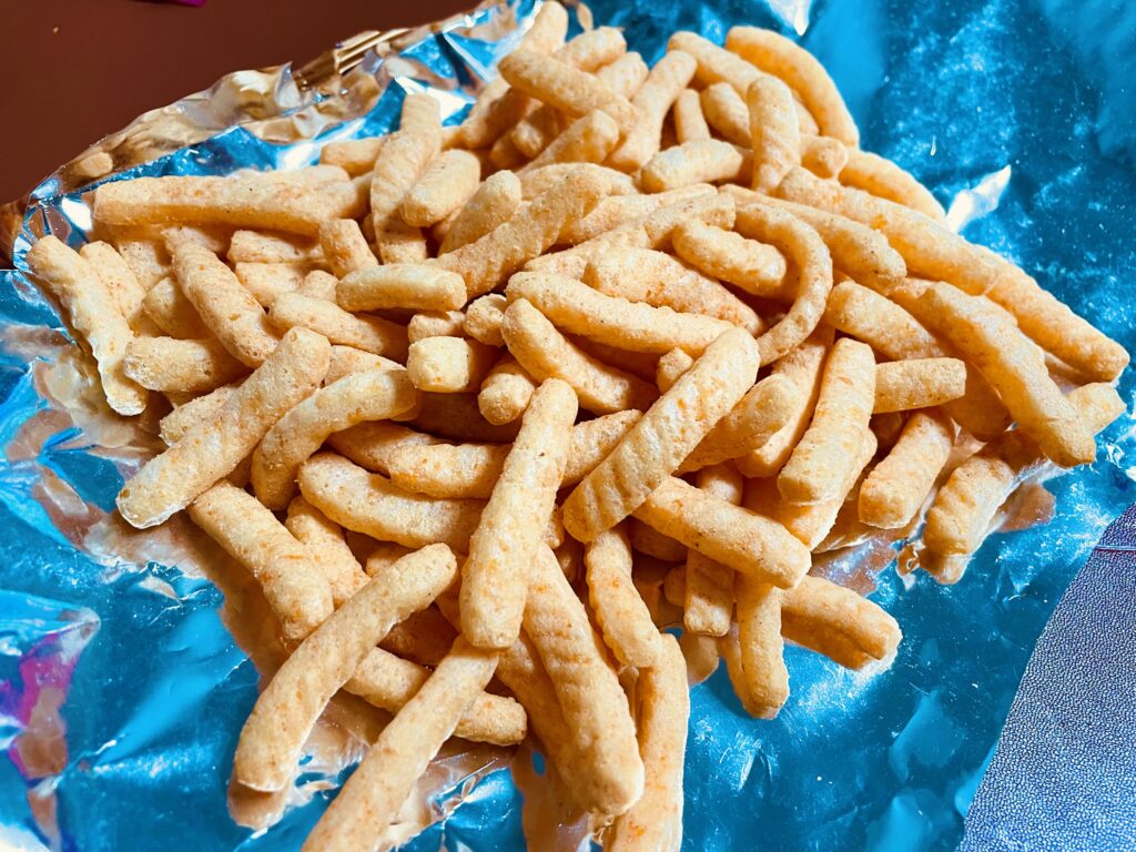 maewoon saewookkang crackers spread out on foil, highlighting the twisted shape and light chili coating that represent spicy korean snack flavors