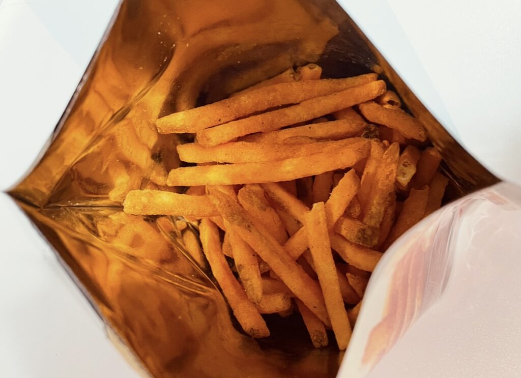 When the bag is opened, long potato sticks coated with red seasoning are visible inside.
Their shape and vivid color resemble French fries, visually capturing the appeal of Spicy Korean snack flavors
