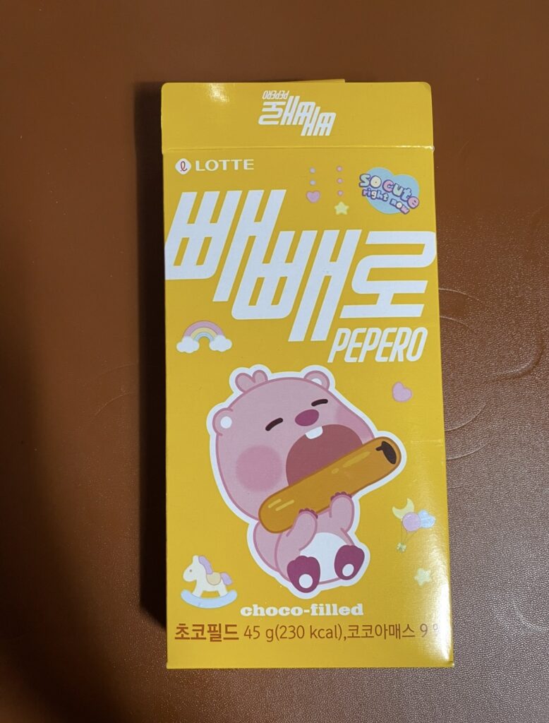 Front view of the Pepero Choco Filled package with a bright yellow design and a cute character illustration, showing the product name clearly