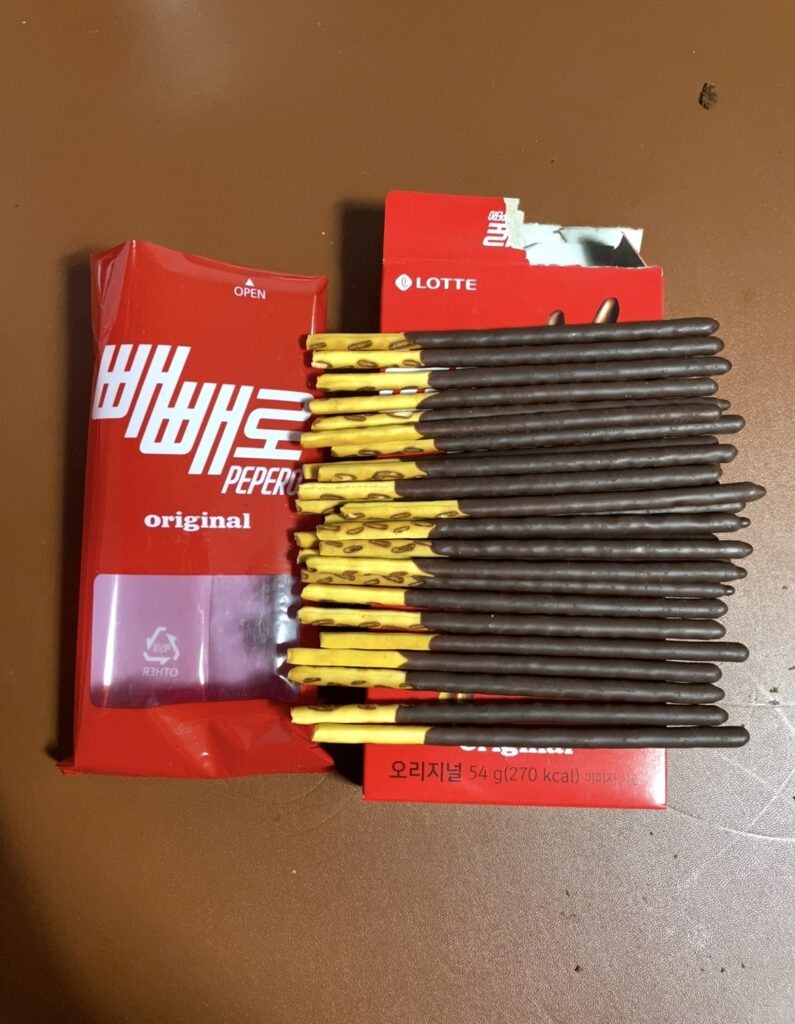 Pepero Original sticks taken out of the package and spread neatly, showing the smooth chocolate coating and giving a natural sense of Korean snack flavors