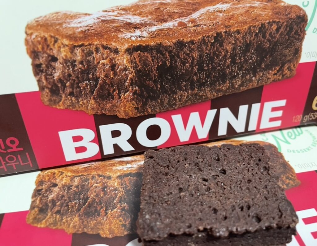 a very close-up photograph clearly showing the moist and dense texture of the brownie surface. this is useful for displaying detailed texture when conducting a korean snack review.