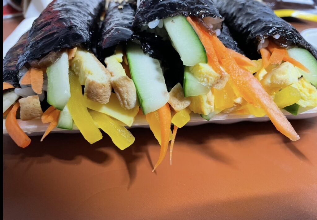 a close-up view of the sliced kkoma gimbap, clearly showing the ratio of rice to fillings typical of a korean seaweed rol